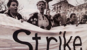 four nurses holding a banner that says "strike"