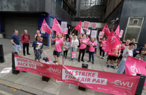 picket line of workers of the CWU union, mostly dressed in pink with a pink banner