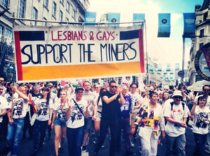 large group on march holding banner "Lesbians & gays support the miners"